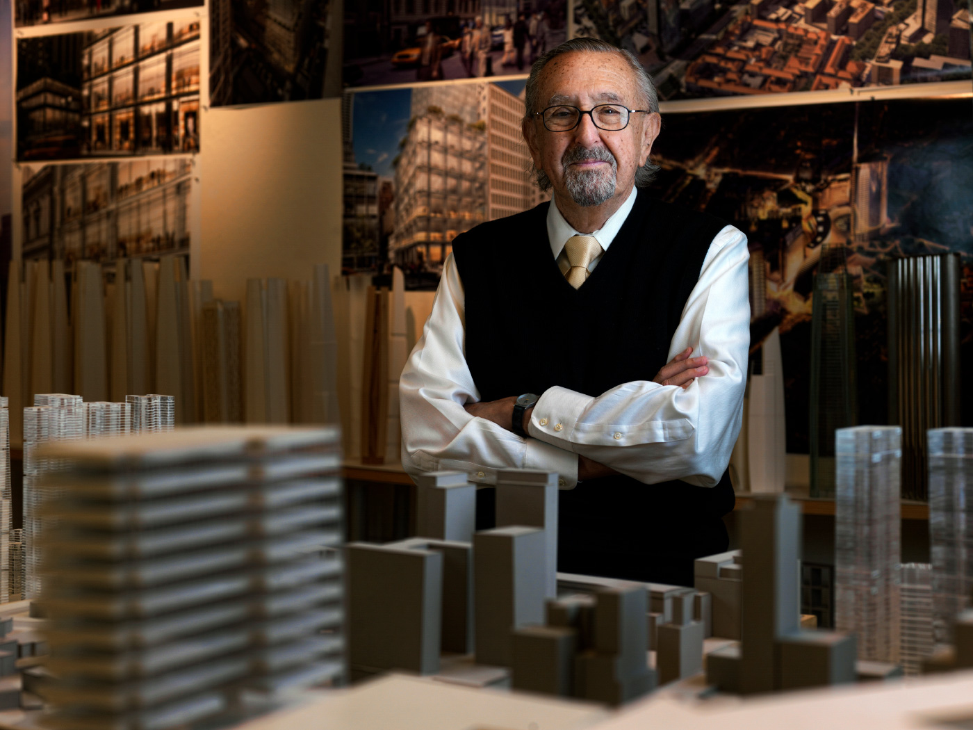 An older man, César Pelli, standing among building models