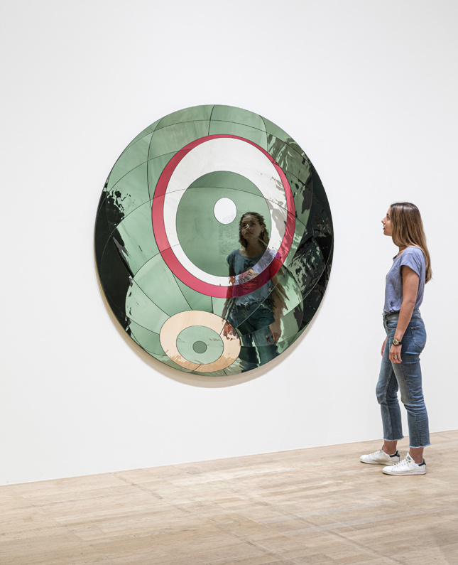 A woman staring into a green circular mirror