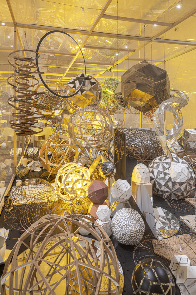 Various geodesic dome and spheres of different materials suspended inside of a box
