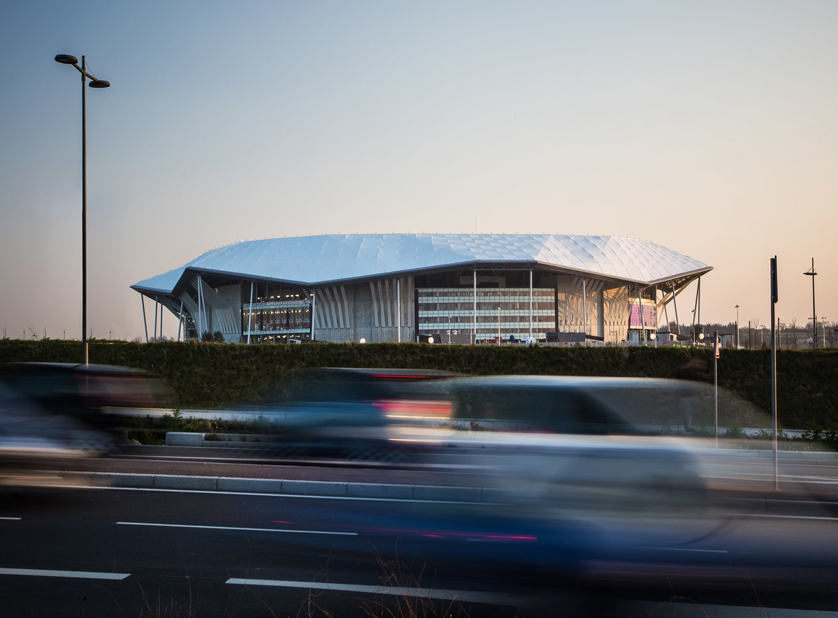 View from highway of white-capped World Cup stadium in twilight