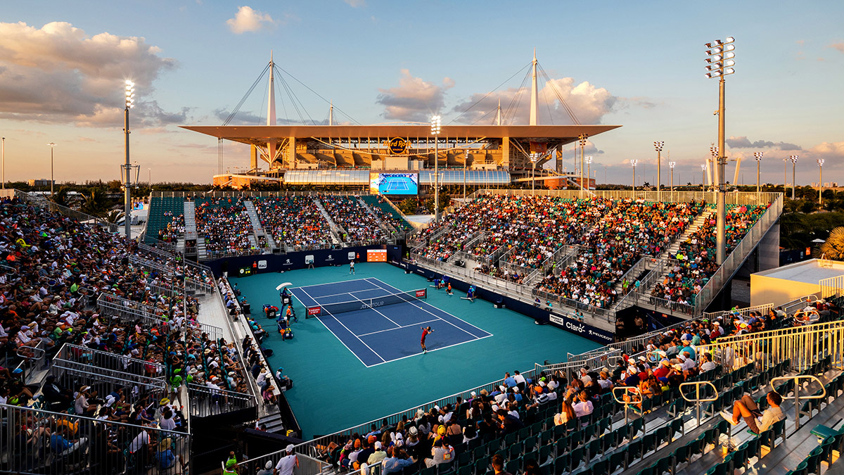 Image of tennis court stadium beneath large football stadium