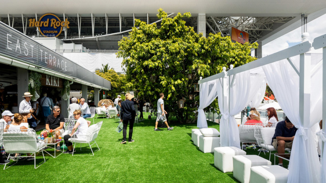 View of turf-covered plaza with white cabanas and food vendors