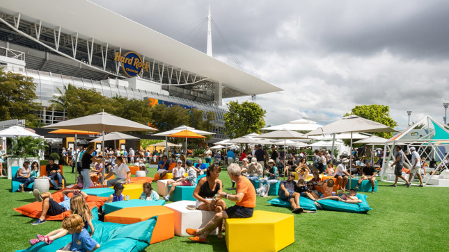 View of turf-covered plaza with yellow, orange, white, and bright blue seating blocks