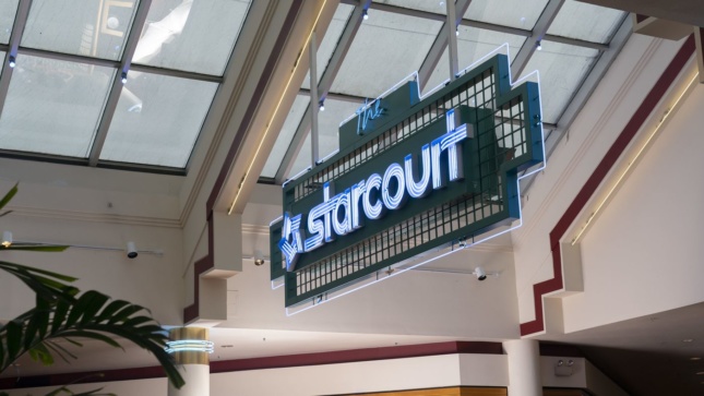 Neon sign that says "Starcourt" hung from ceiling in mall, a prop from Stranger Things 3