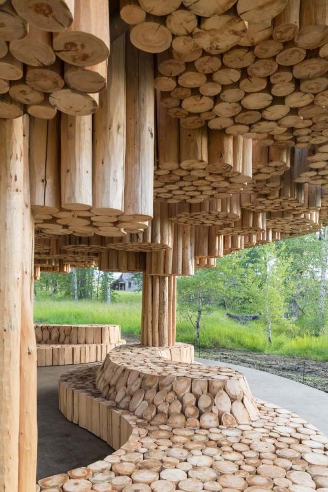 Suspended bundles of logs inside of an open-air pavilion