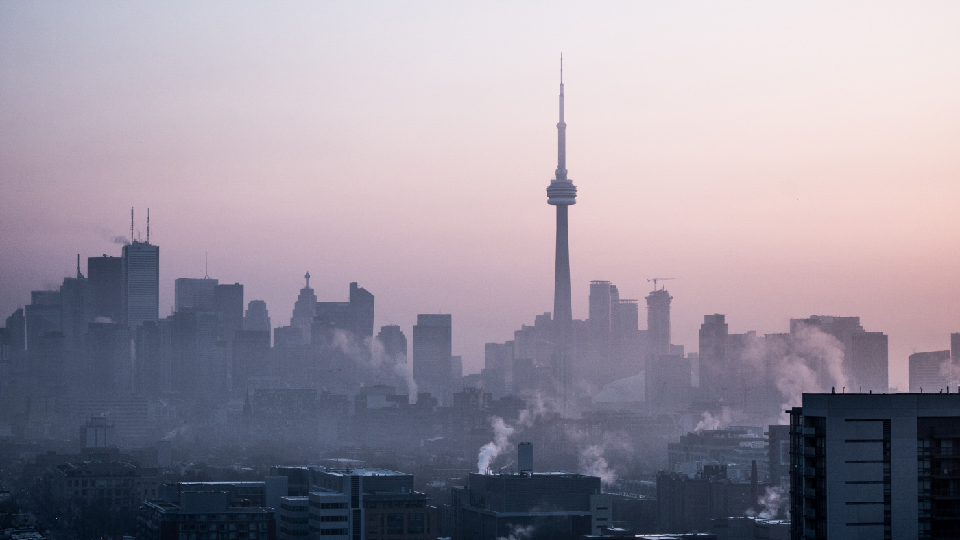 A city's skyline sheathed in smoke, with a red haze in the background
