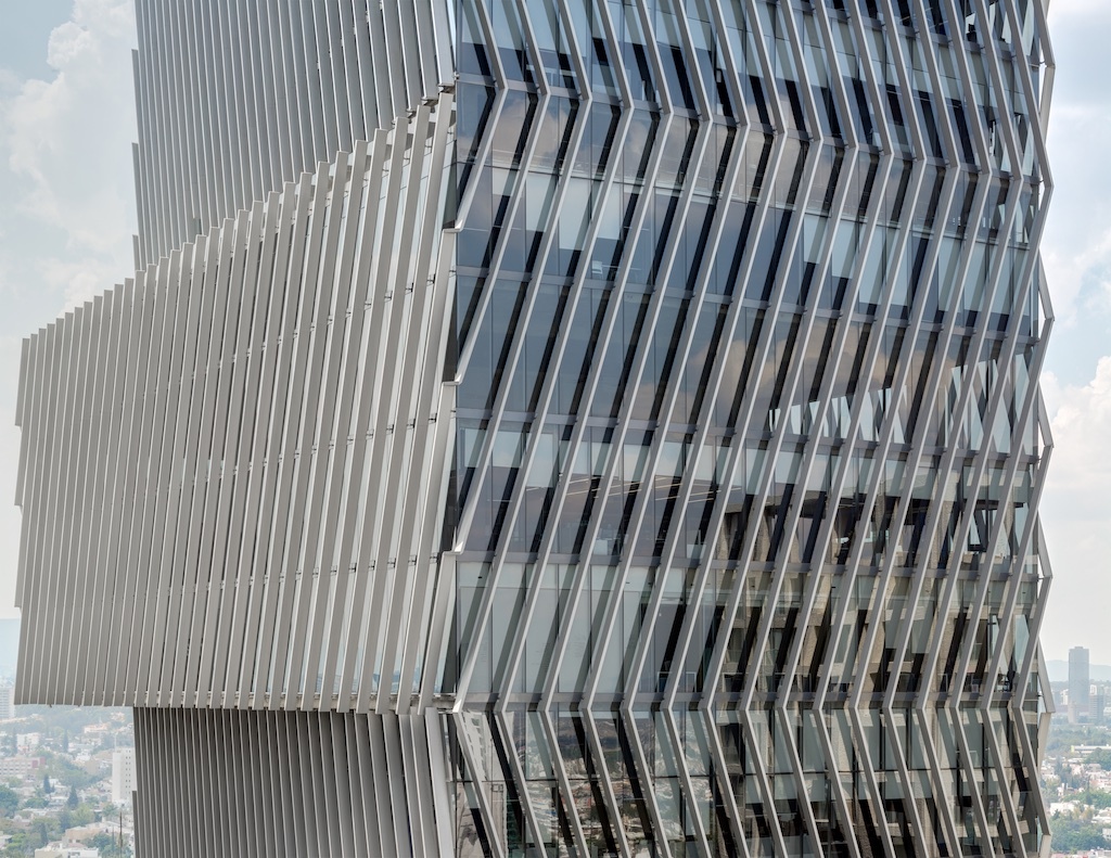 Oversize glass cladding a building with offset volumes and slanted louvers