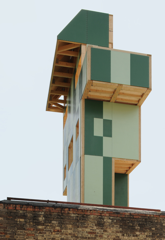 A tall timber pavilion clad in green panels