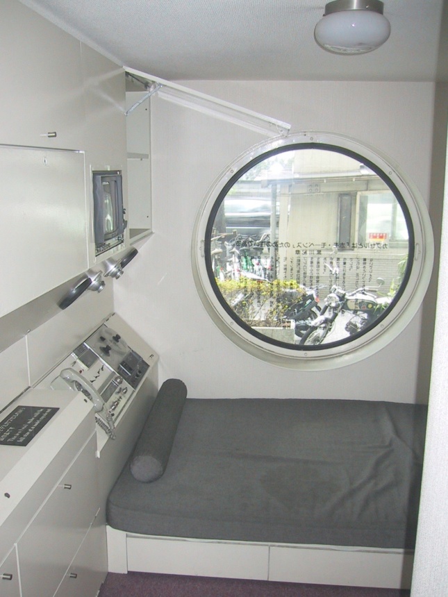 Interior view of a tiny room with porthole