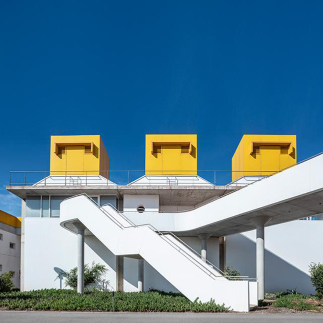 Exterior image of building with yellow roof structures and a white staircase protruding from side