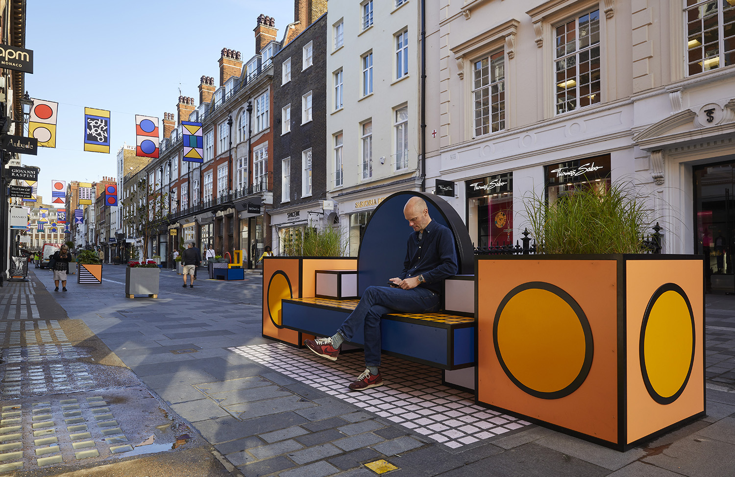 Photo of a man sitting on an orange bench at the London Design Festival