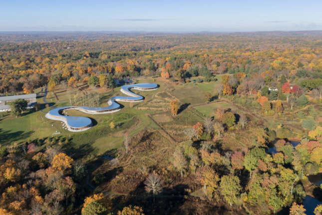 Aerial image during fall season of snake-like building in open field 
