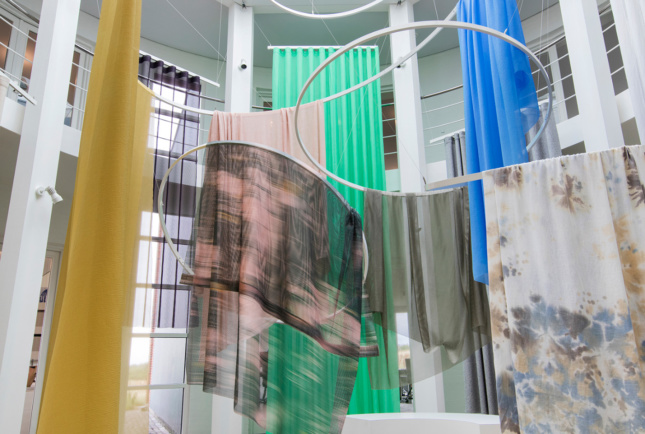 Different fabrics from Kvadrat suspended from metal rings