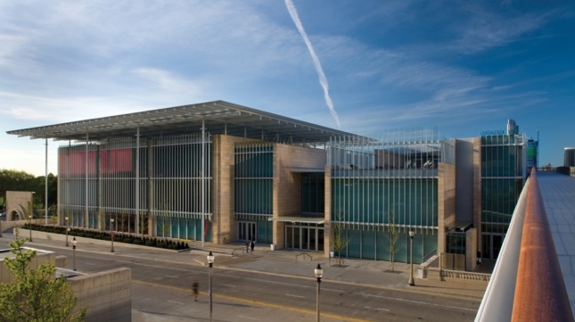View from walking bridge lookin at contemporary museum architecture with glass windows, concrete siding, a roof canopy and slatted fins covering facade