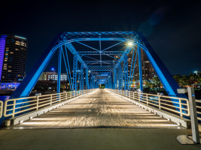 A blue pedestrian bridge is illuminated at night.