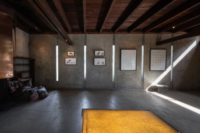 Interior of a blank concrete gallery space with yellow tables