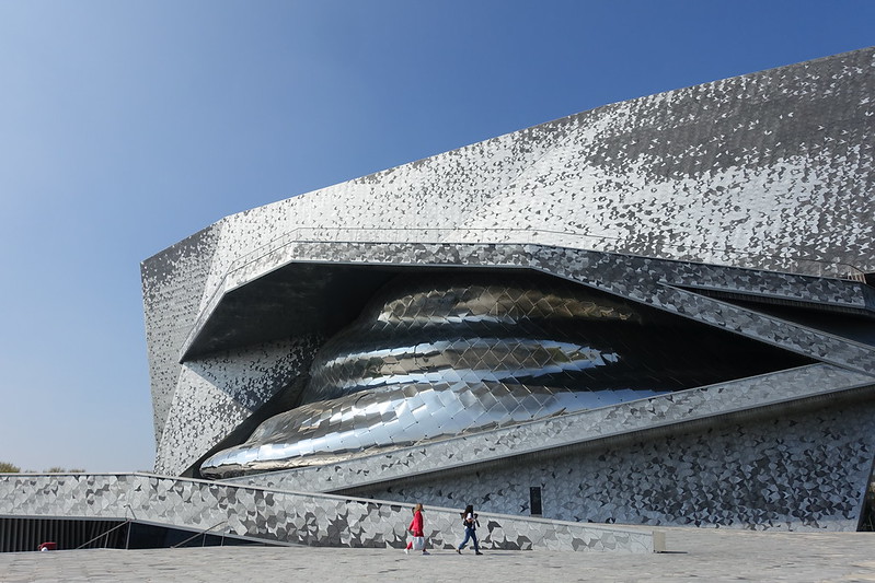 Exterior shot of curvaceous and shiny concert hall against blue sky