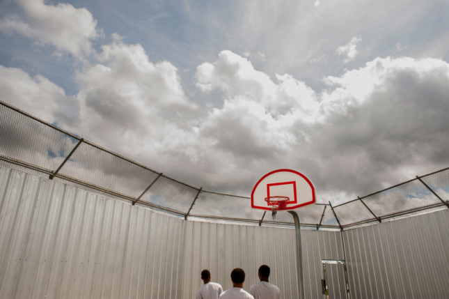 Inmates looking towards the sky in a prison basketball court