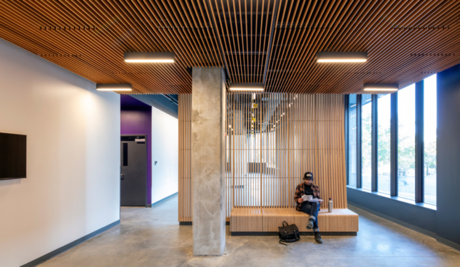 Students in a concrete lobby on timber furniture