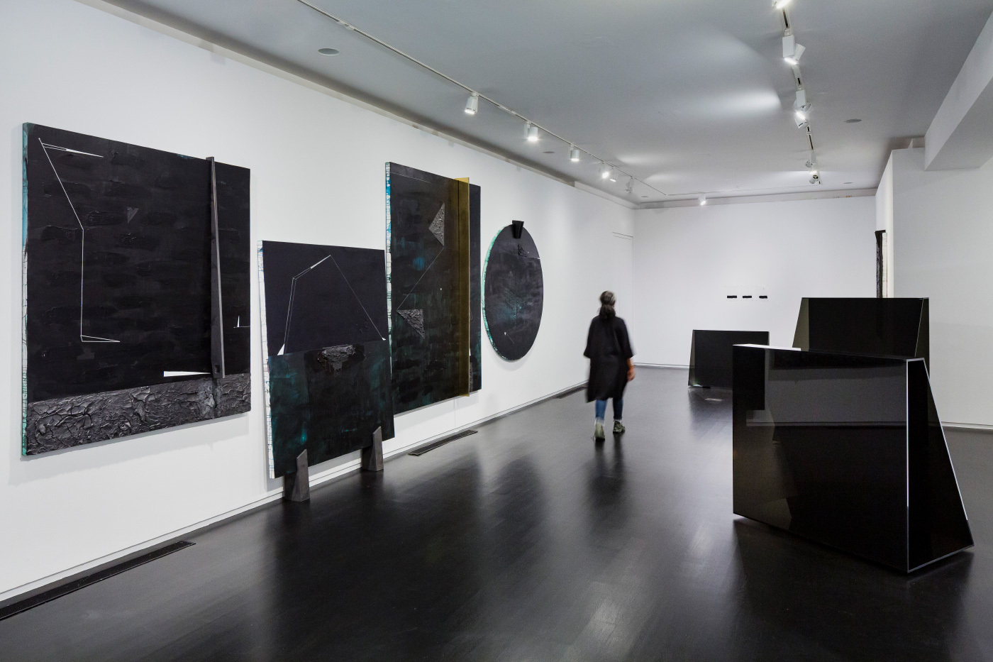 Installation view of black paintings by Torkwase Dyson on a white background