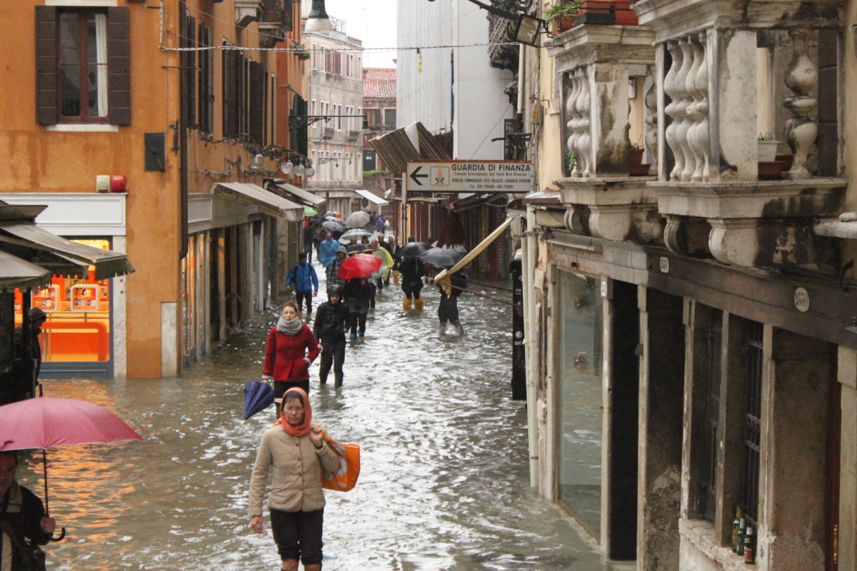 People walk through a flooded street in Venice