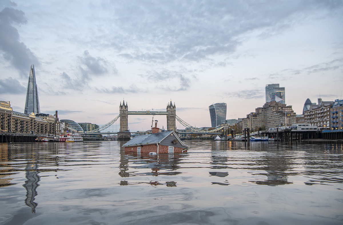 Photo of a house submerged in the River Thames by Extinction Rebellion, with towers in the background