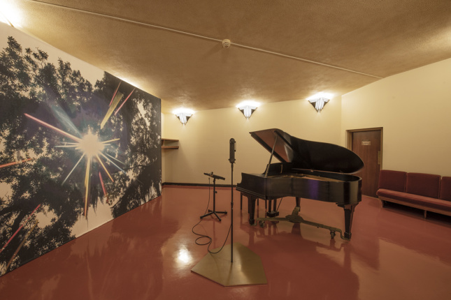 A piano next to a mural of a forest