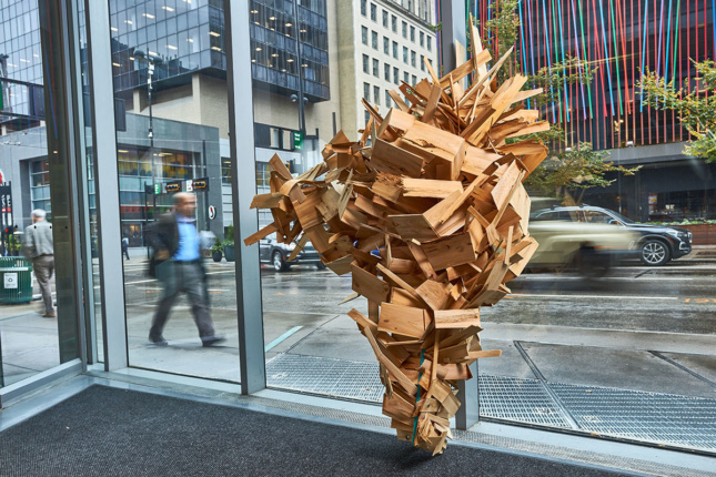 Geometric wooden sculpture against glass panel walls