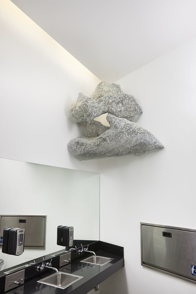 Sculpture above bathroom sink of two large stones suspended in the corner