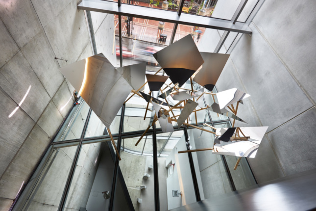 Interior photo of a metal sculpture suspended in a concrete atrium