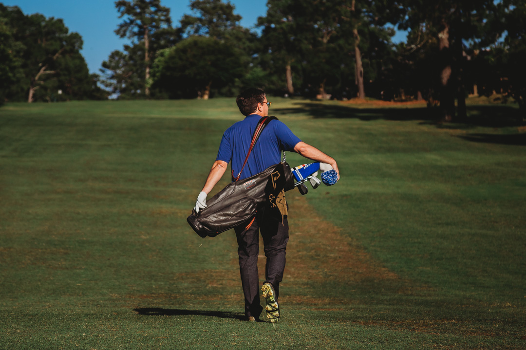 Image of man walking on golf course carrying his bag