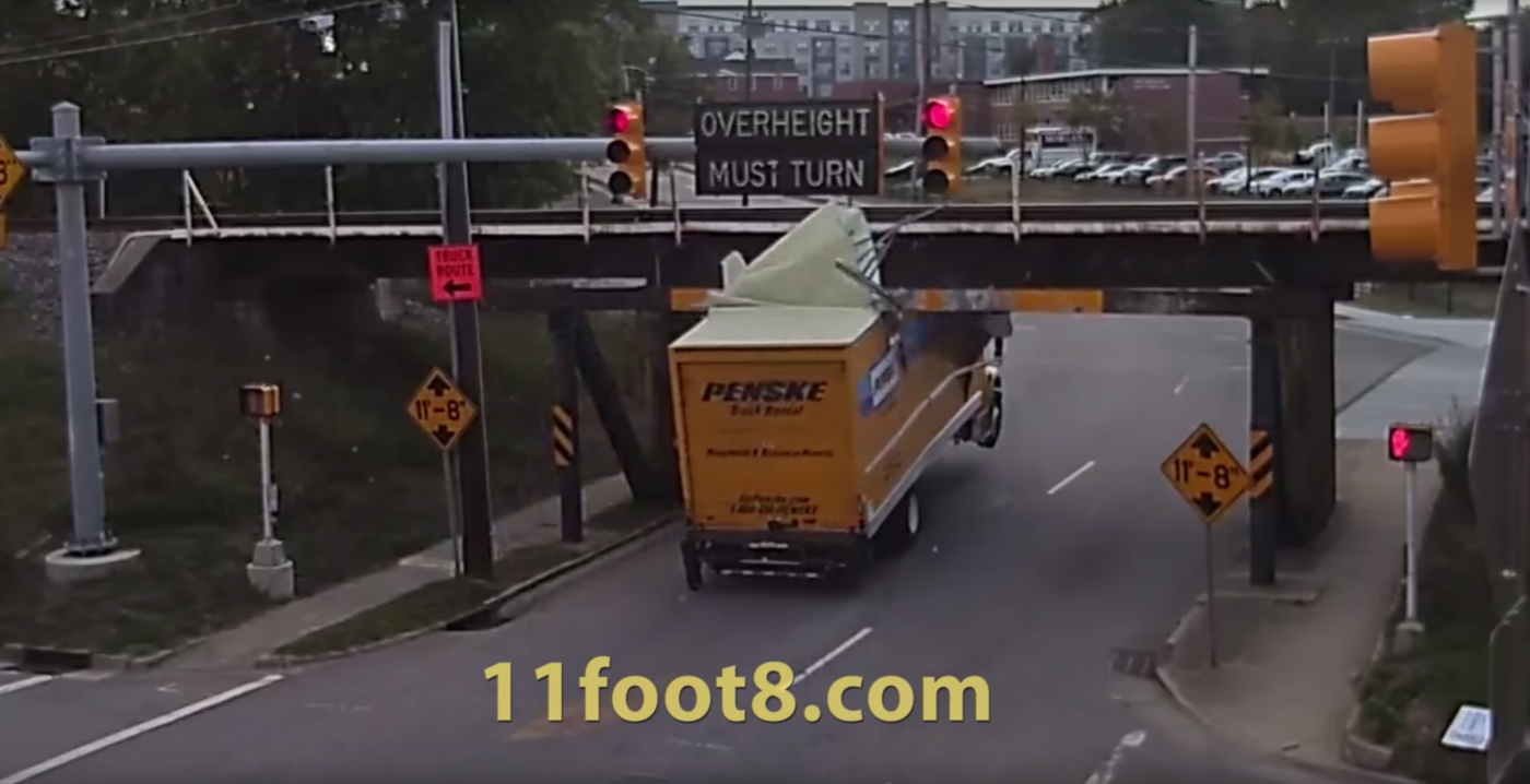 A truck getting wedged under a bridge