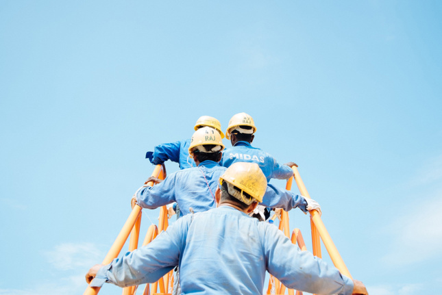 Image of workers climbing ladder together