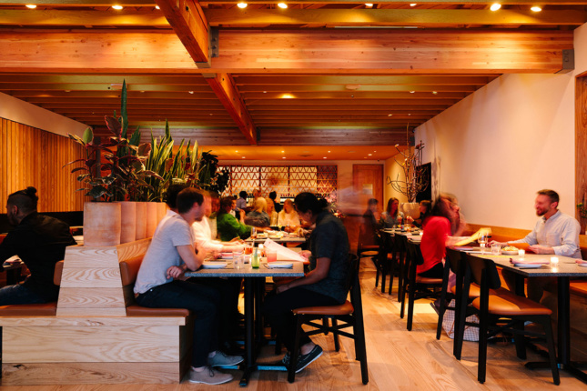 Image of wooden interior with people dining at small tables