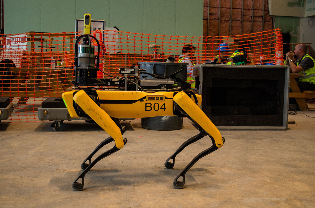 A yellow four-legged robot dog on a construction site, one of the Spot models from Boston Dynamics