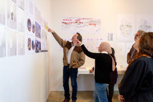 A group of people look at drawings pinned up on a wall for an architecture review