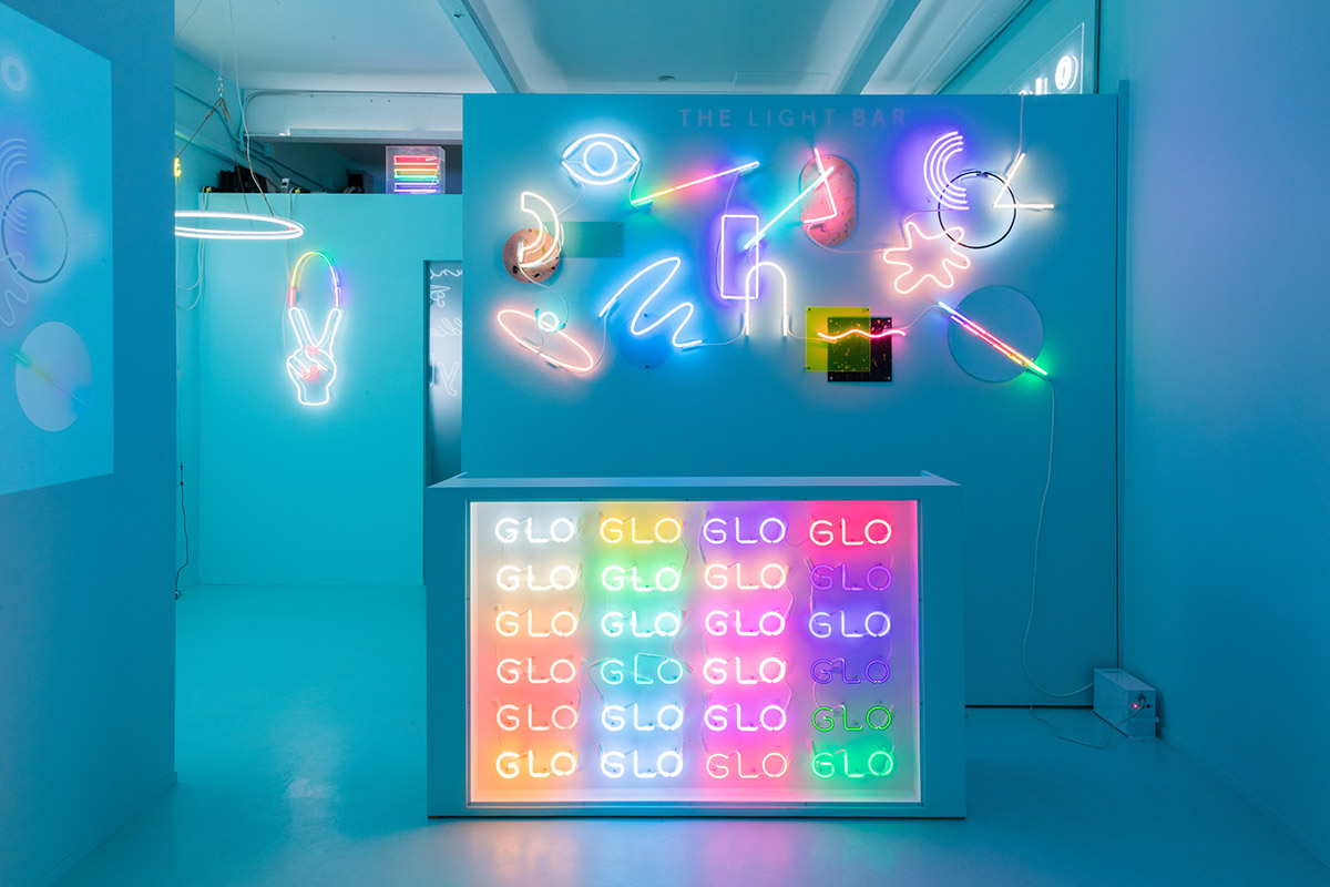 Neon signs that read Name Glo in a teal storefront