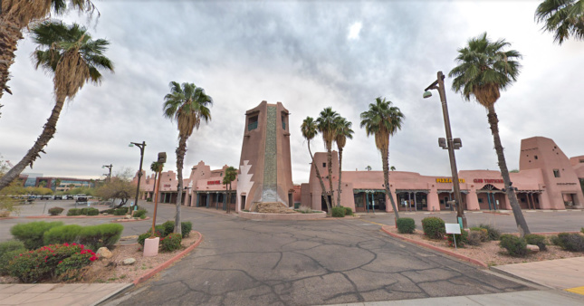 A photo of a strip mall rendered in pink adobe, with a sign that says Papago Plaza