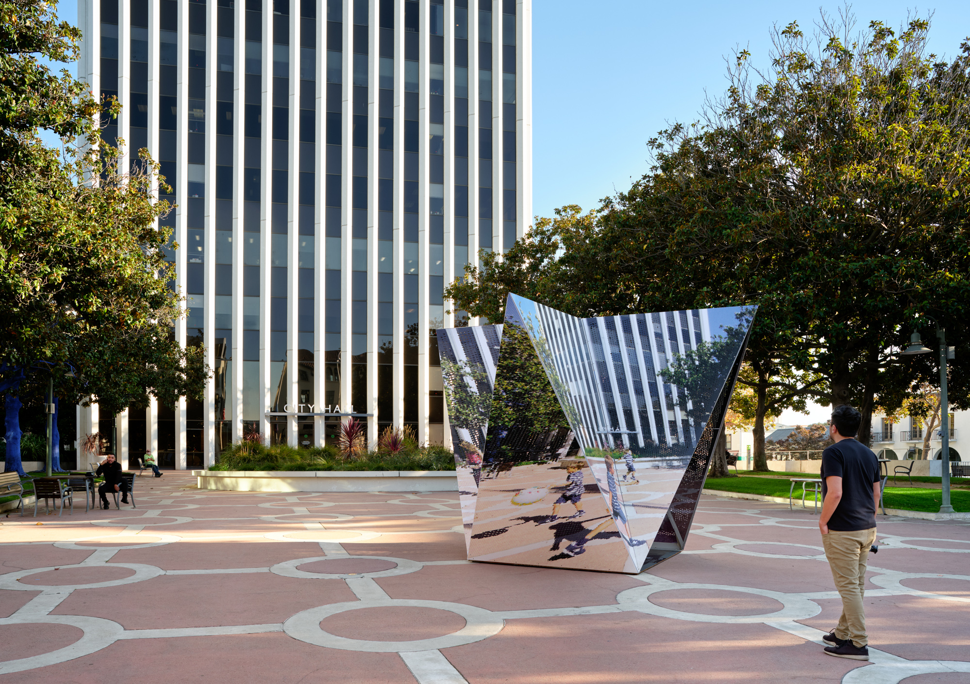 A man walking by a mirrored crystal structure in Palo Alto