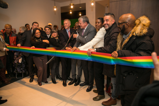 a group of people cut a rainbow ribbon