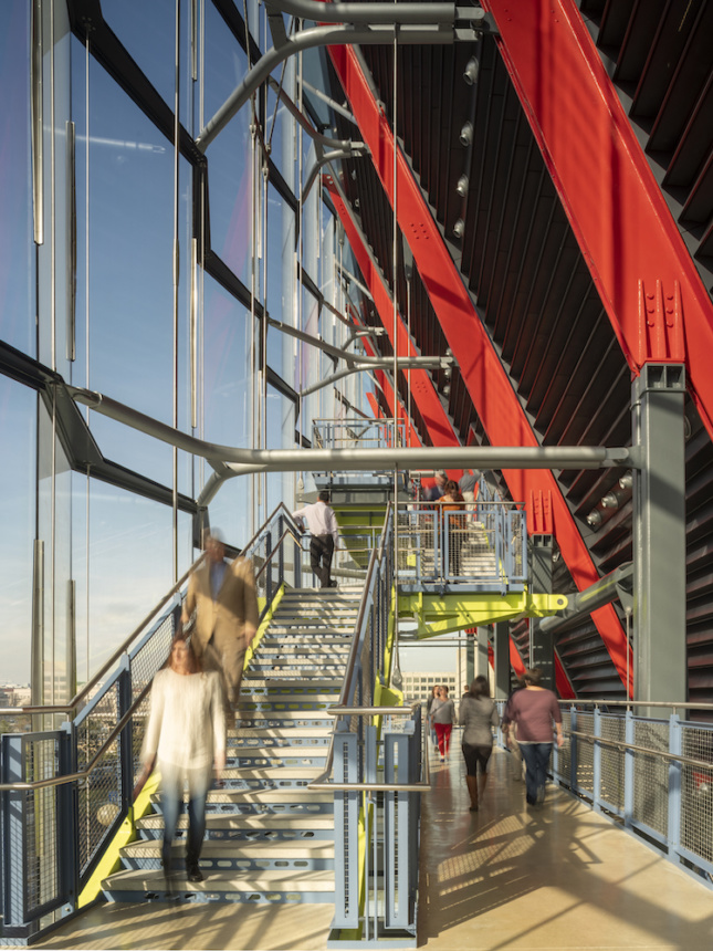 Image of stairwell between a red curtain wall and glass facade