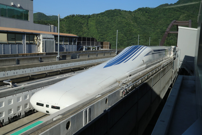 Image of elongated maglev train on rails above ground level, part of a high-speed rail network