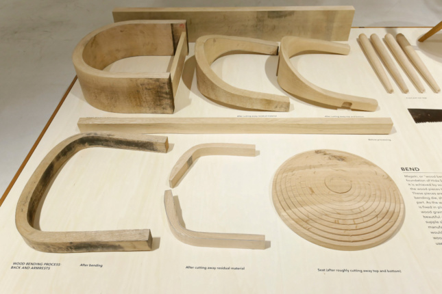 Different pieces of a wood chair laying on a plinth