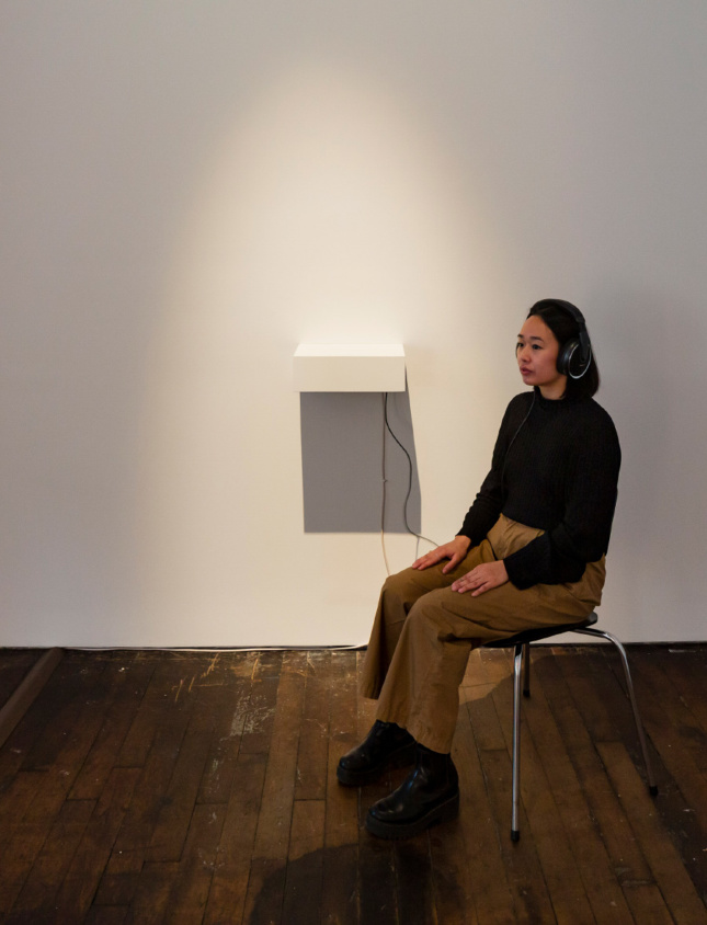 A woman listening to an audiobook in Peter Freeman gallery space