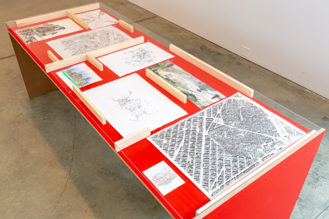 Architectural drawings on a red plinth