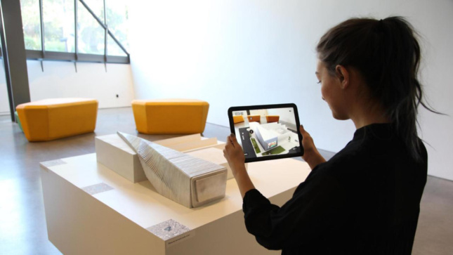 A person using an iPad to view AR effects over a model of the BAMPFA.