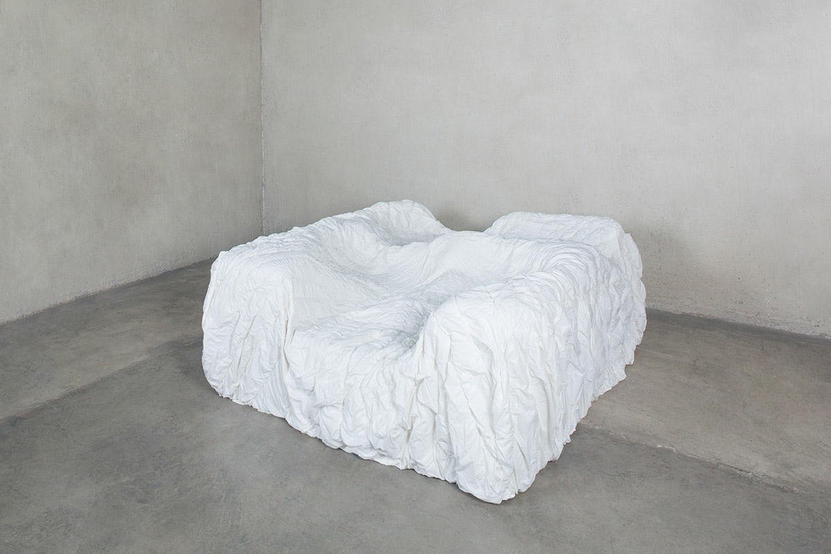 A white couch made from foam on a concrete floor