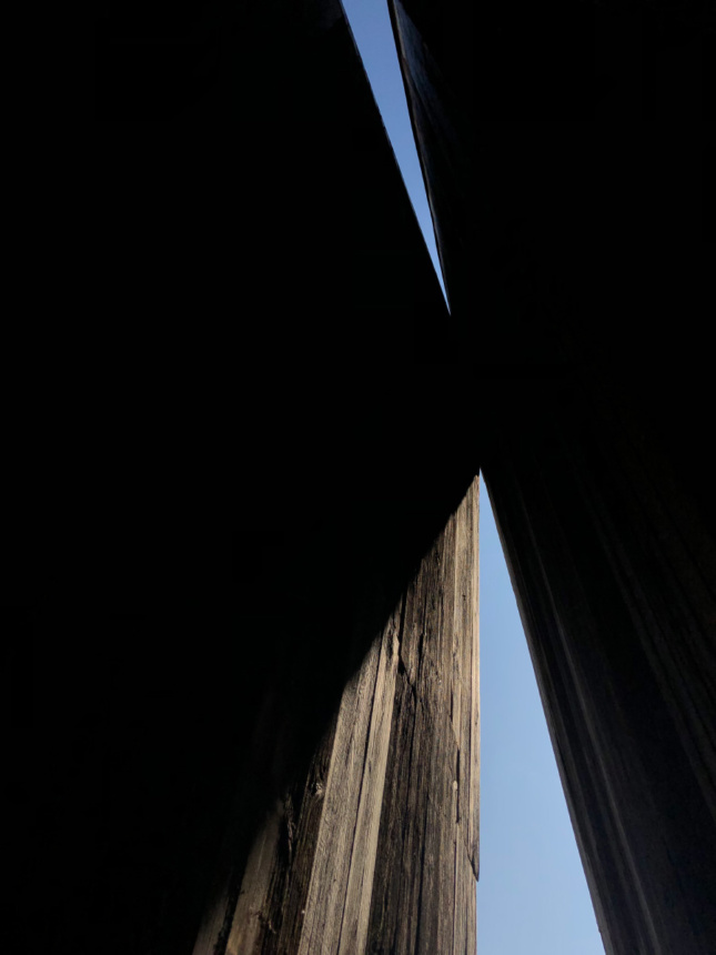 Looking up to the sky through a split in timber