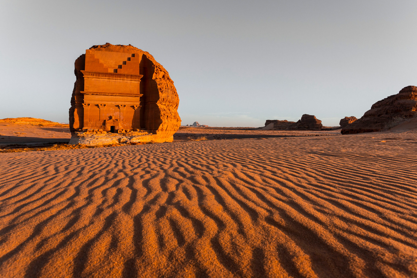 A large facade carved out of a giant boulder in the desert.