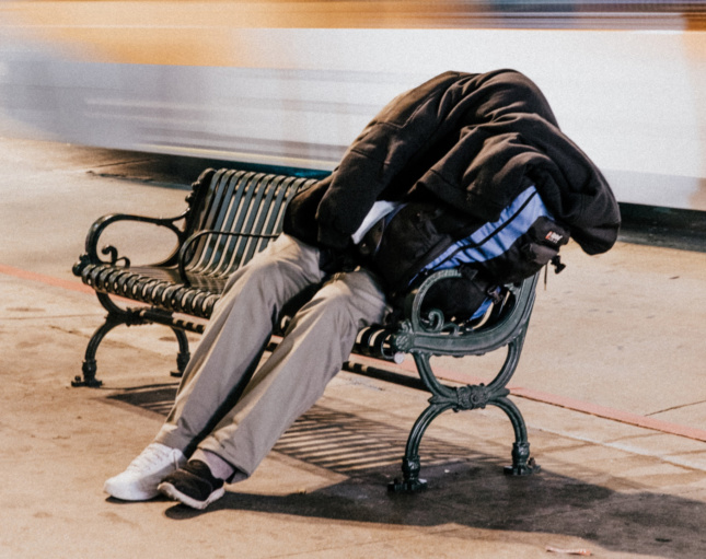 A homeless man sleeping on a bench